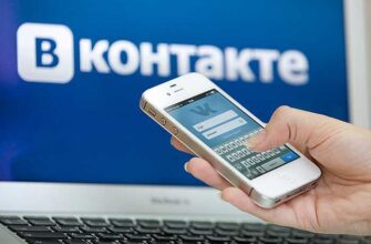 Смартфон в руке на фоне ВКонтакте